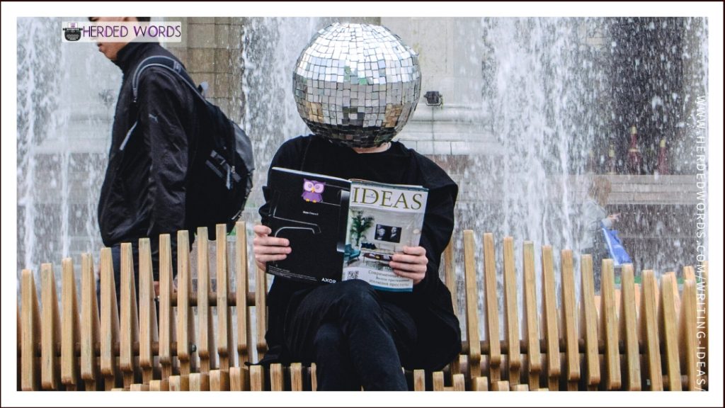 A person sitting on a bench reading "IDEAS" magainze. Did I mention they have a disco ball for a head?