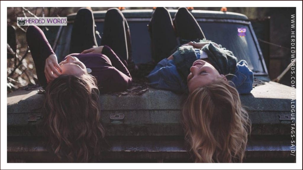 two girls laying on a car talking