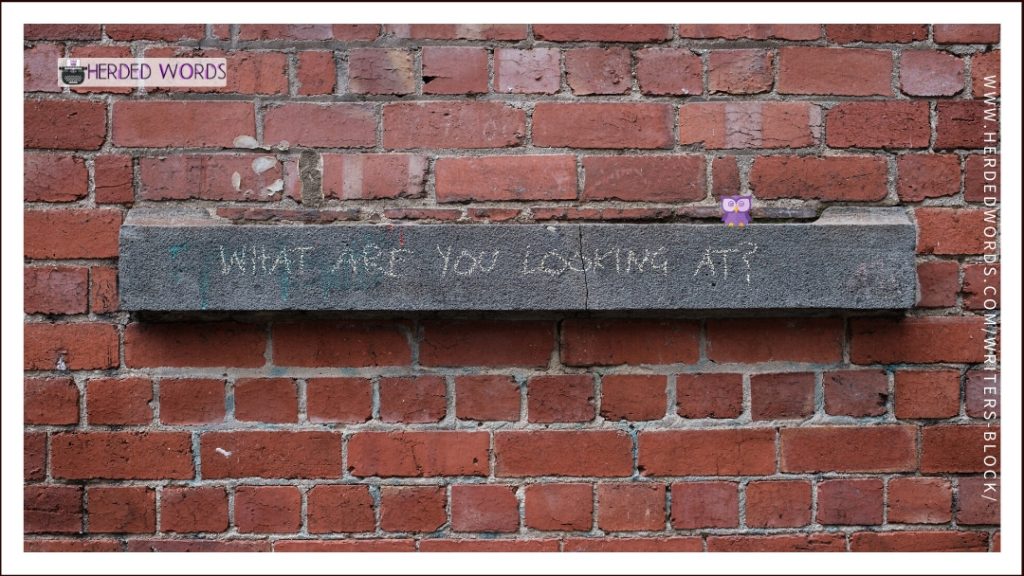 A mantel on a brick wall that says "What are you looking at?"
