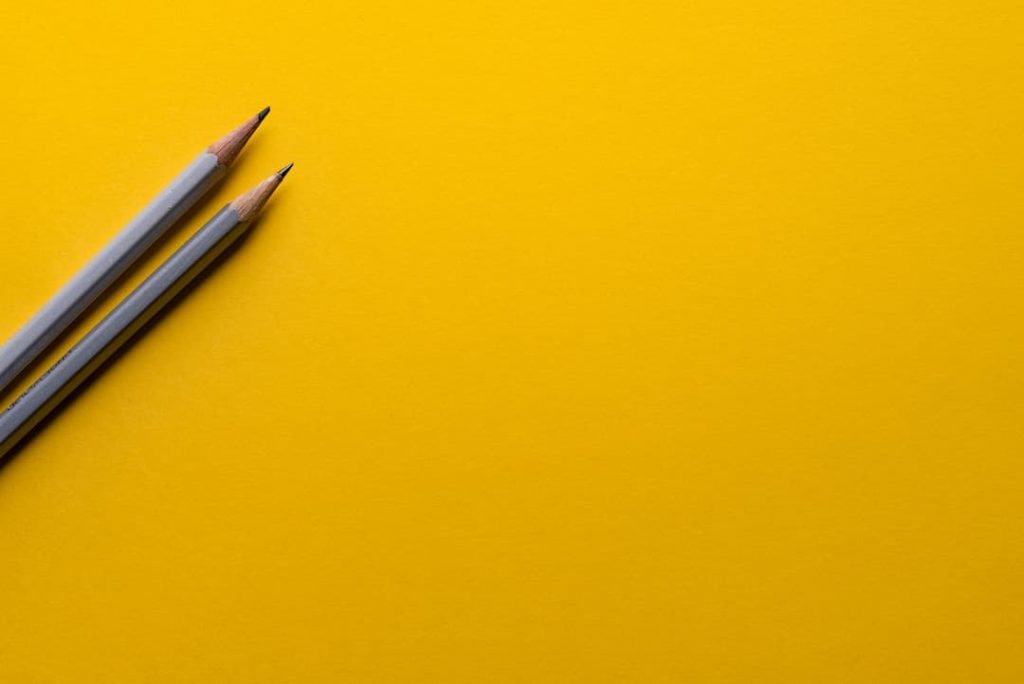 a yellow background with 2 grey pencils